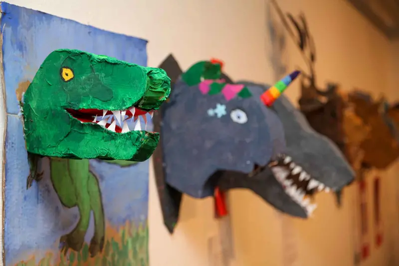 Färgglada Dinosauriehuvuden i papp uppsatt på vägg, pyssel