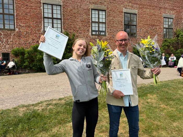 Bild på två person som mottagit diplom och blombukett. Står framför Svaneholm slott.
